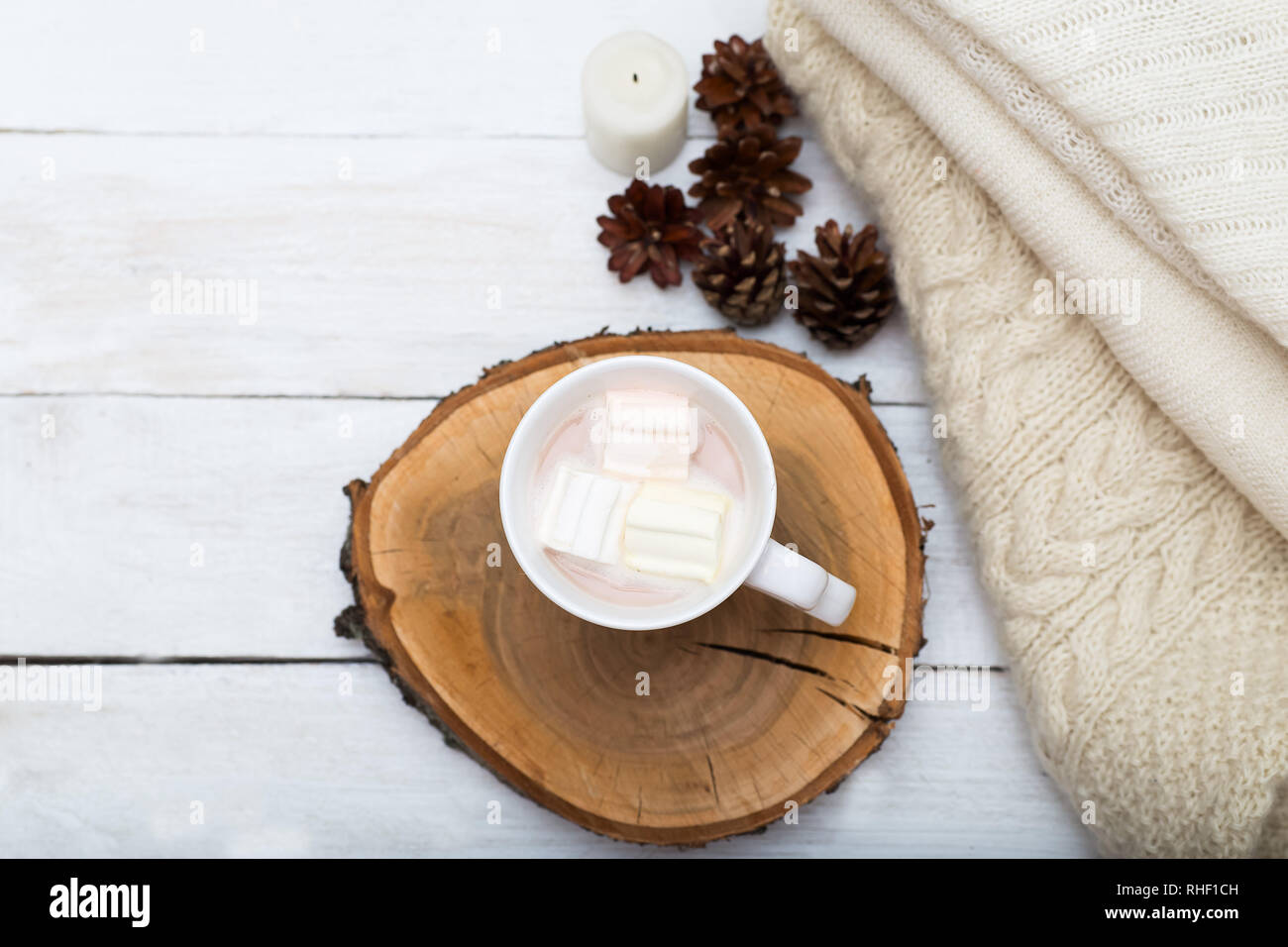 Tasse de chocolat chaud avec des guimauves, et une pile de choses tricotées sur un fond de bois blanc Banque D'Images