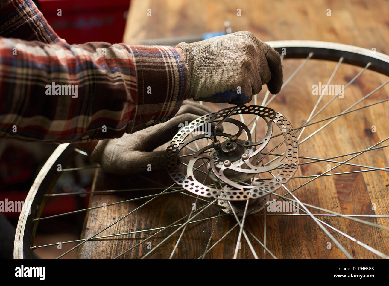 Portrait de femme en travail mécanique atelier de réparation de vélos, la réparation de roues de vélo militaire à l'aide de l'outil, en portant des vêtements et des gants Banque D'Images