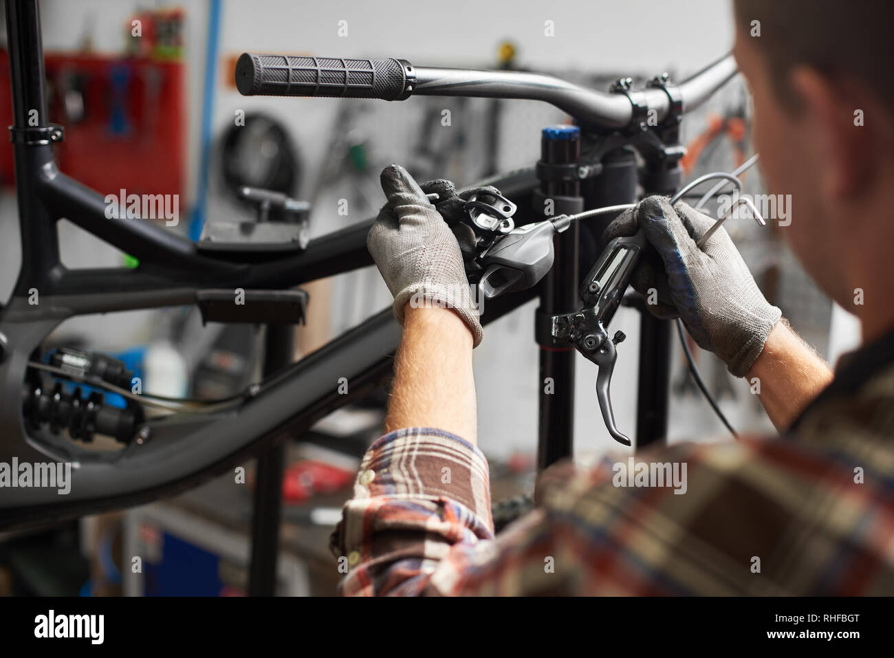 Cropped shot de réparateur professionnel travaillant en atelier de réparation de vélos, mechanic repairing bike à l'aide de l'outil, en portant des gants protecteurs Banque D'Images