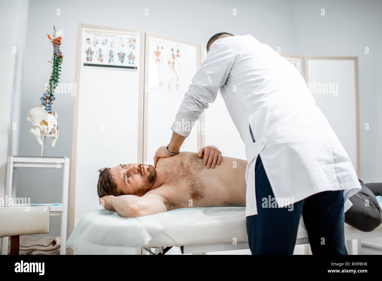 Physiothérapeute senior professionnel faire le traitement manuel d'un homme dans le cabinet de clinique de réhabilitation Banque D'Images