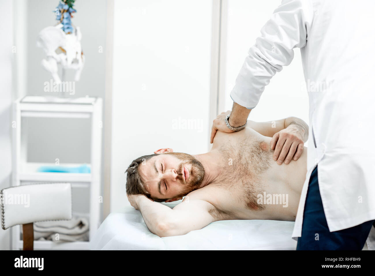 Physiothérapeute senior professionnel faire le traitement manuel d'un homme dans le cabinet de clinique de réhabilitation Banque D'Images