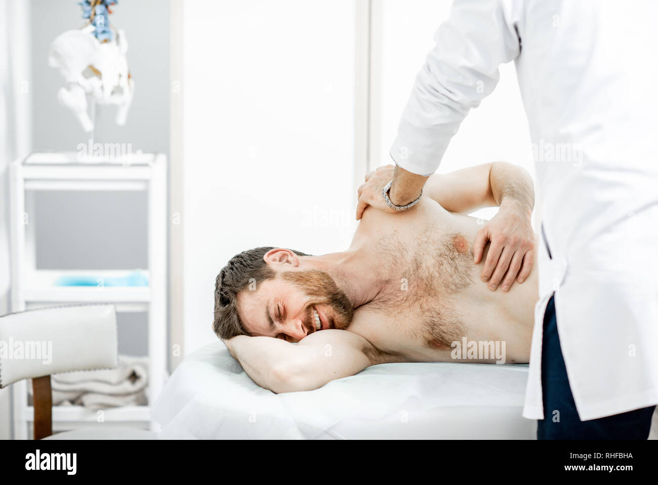 Physiothérapeute senior professionnel faire le traitement manuel d'un homme dans le cabinet de clinique de réhabilitation Banque D'Images