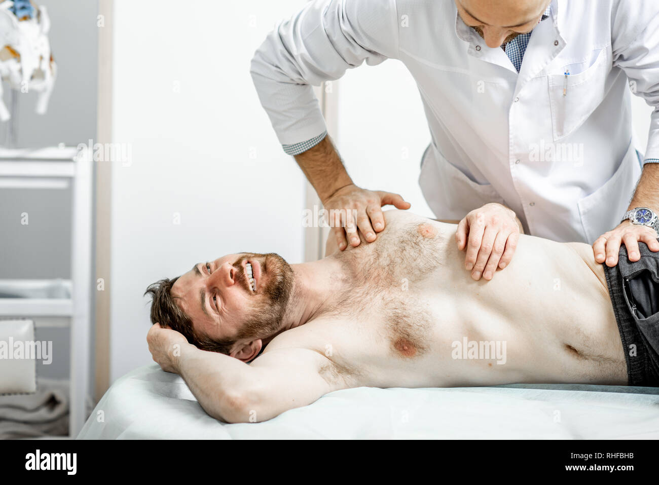 Physiothérapeute senior professionnel faire le traitement manuel d'un homme dans le cabinet de clinique de réhabilitation Banque D'Images