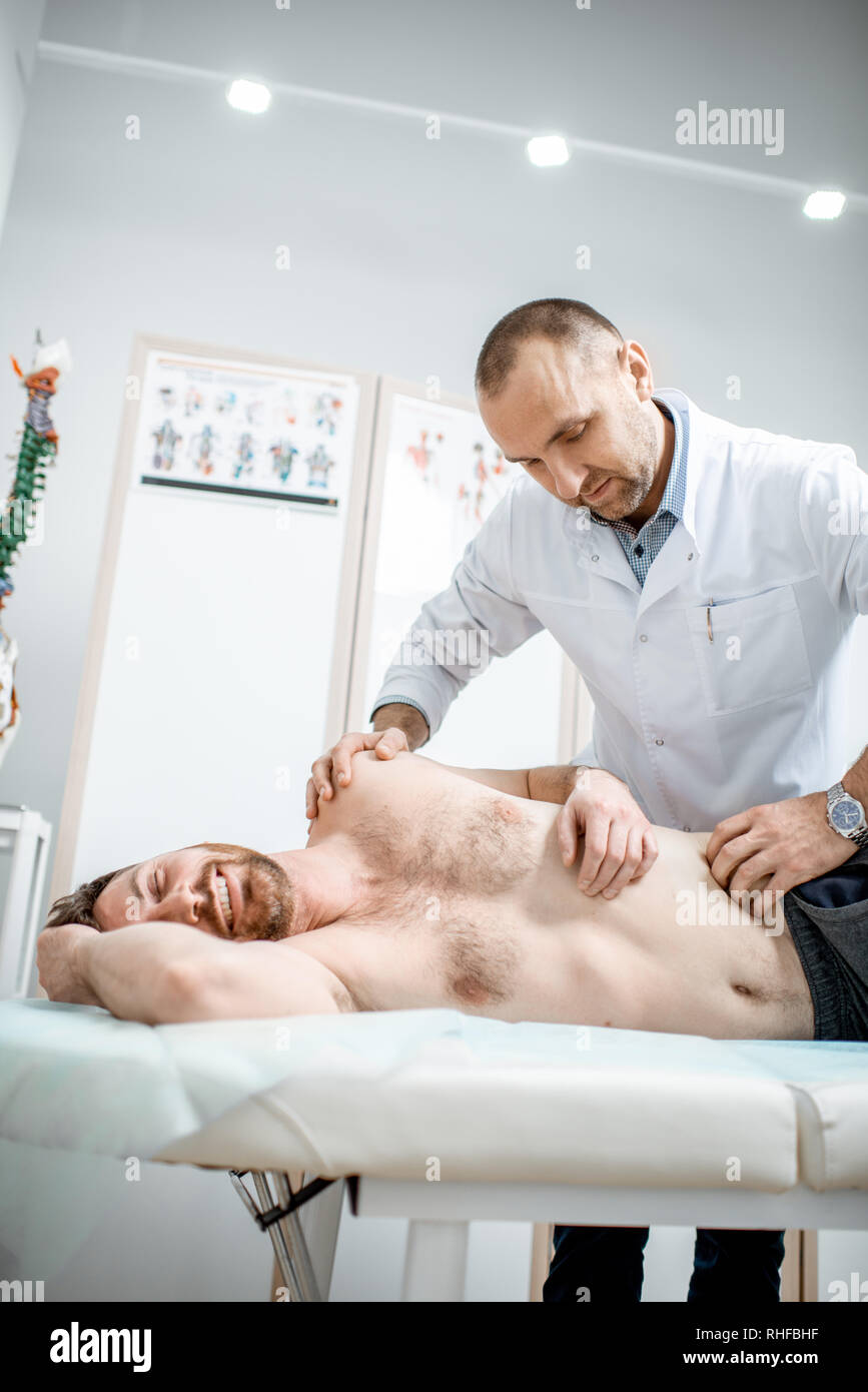 Physiothérapeute senior professionnel faire le traitement manuel d'un homme dans le cabinet de clinique de réhabilitation Banque D'Images