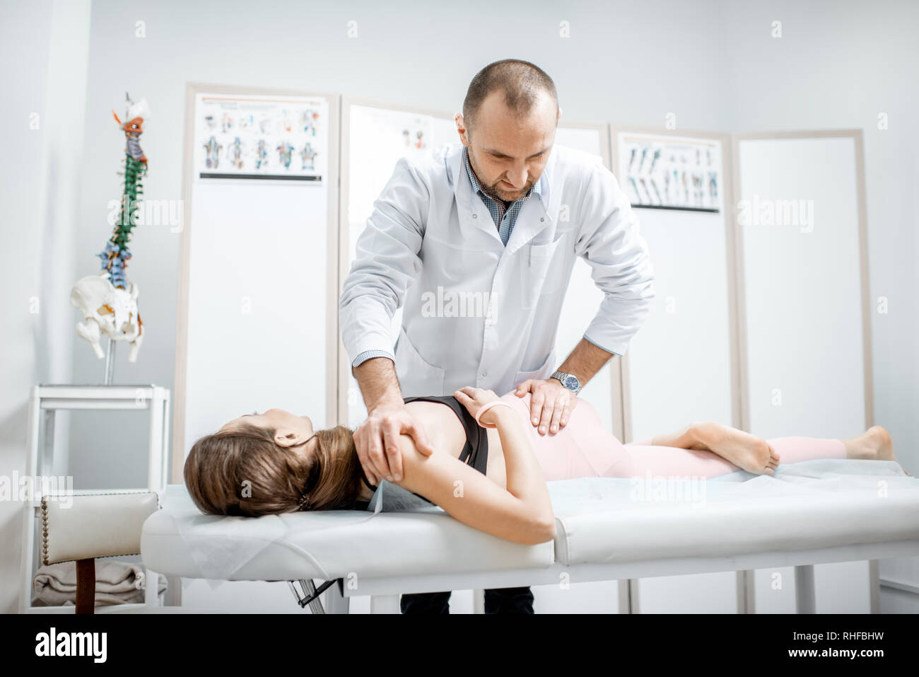 Physiothérapeute senior professionnel faire le traitement manuel d'une jeune femme avec des problèmes de dos dans le cabinet de clinique de réhabilitation Banque D'Images