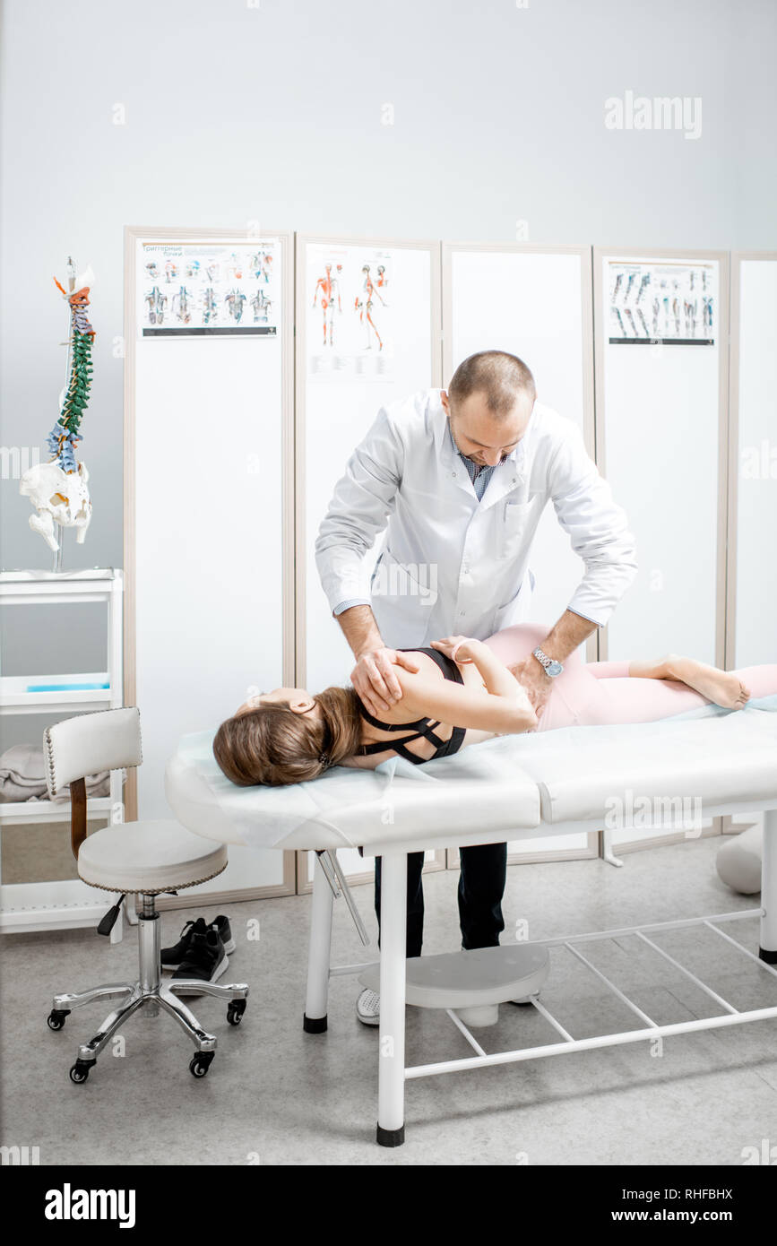 Physiothérapeute senior professionnel faire le traitement manuel d'une jeune femme avec des problèmes de dos dans le cabinet de clinique de réhabilitation Banque D'Images