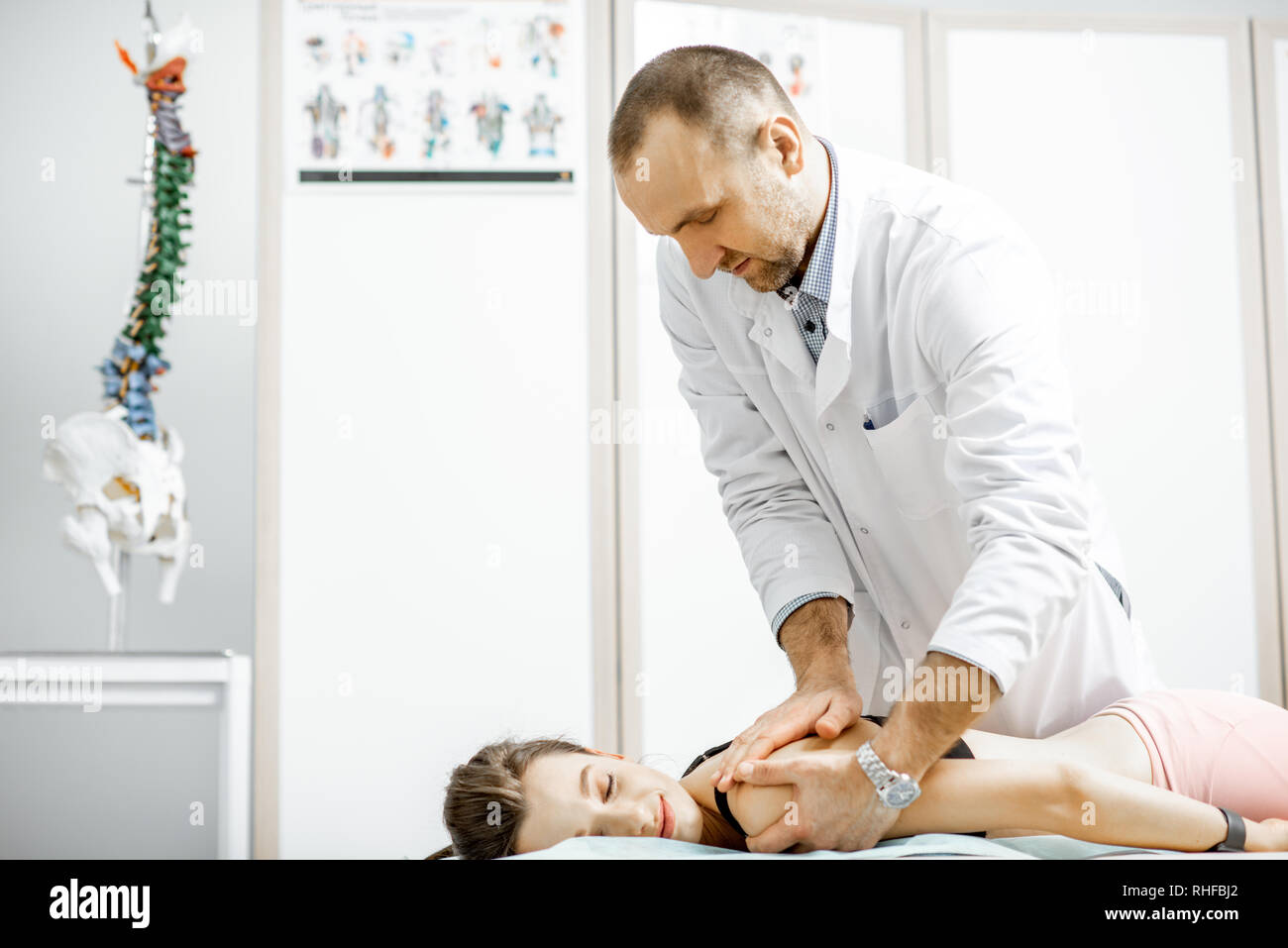 Physiothérapeute senior professionnel faire le traitement manuel d'une jeune femme avec des problèmes de dos dans le cabinet de clinique de réhabilitation Banque D'Images