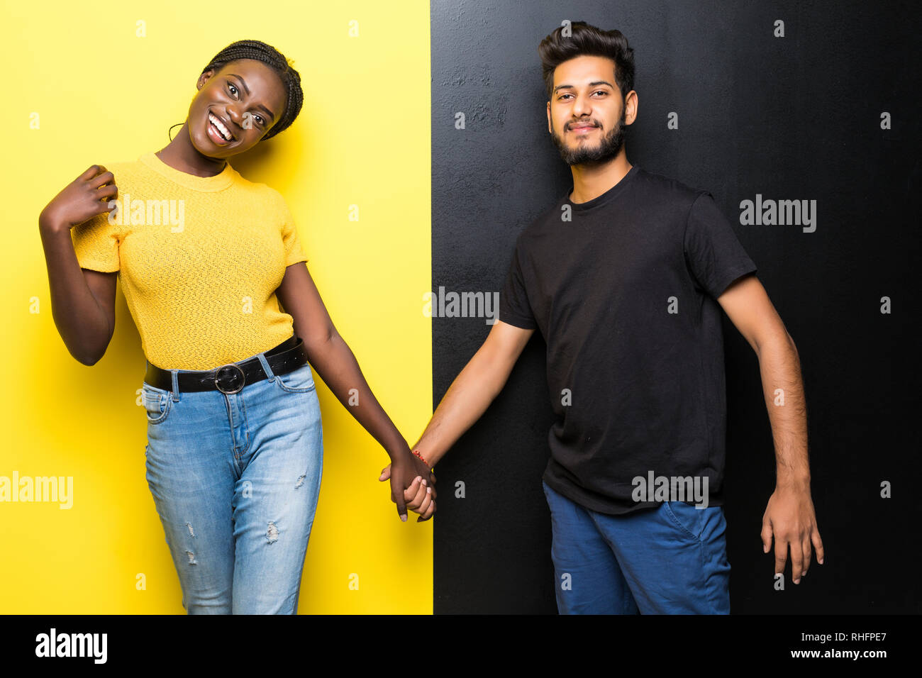 Young mixed race couple indien, homme et femme africaine s'occupe de l'article sur fond noir jaune Banque D'Images