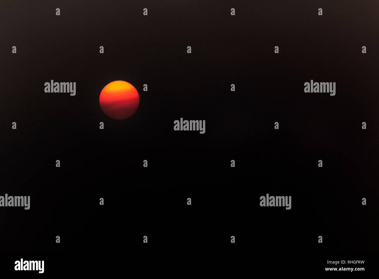 Le soleil capturées à l'aide d'un filtre, montrant les nuages passant dans front​ d'un soleil orange Banque D'Images