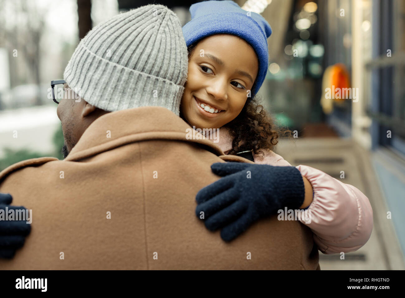 Jolie fille aux yeux noirs portant des gants et chapeau hugging son père Banque D'Images