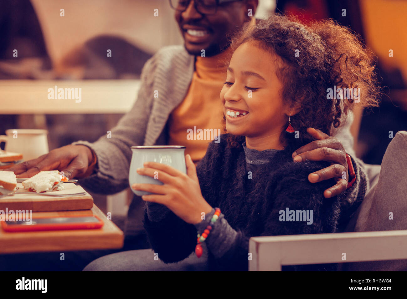 Cute fille joyeuse portant des accessoires colorés holding cup of tea Banque D'Images