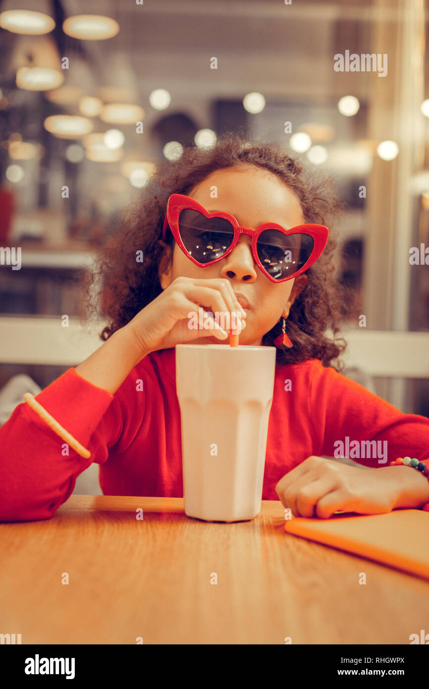 Curly girl wearing accessoires colorés milkshake potable Banque D'Images