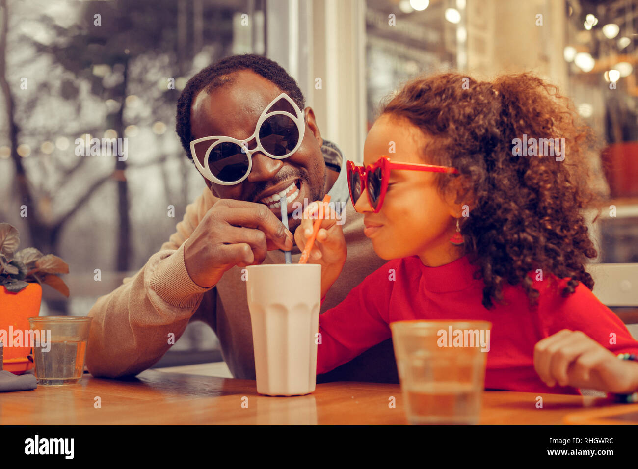 Cheerful heureux père portant des lunettes lumineuses et milkshake potable Banque D'Images
