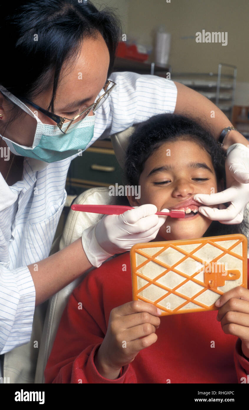 Dentiste montrant jeune fille comment se brosser les dents correctement in front of mirror Banque D'Images