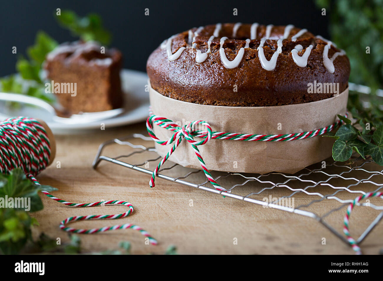 Vacances de Noël à la cannelle gâteau bundt épice, enveloppé comme un cadeau avec le rouge, le blanc et le vert de la ficelle et du papier brun, sur grille de refroidissement sur le bois. Banque D'Images
