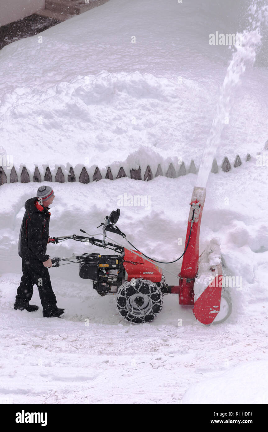 L'homme prend sur la neige avec un chasse-neige, neige sur les côtés haut Banque D'Images