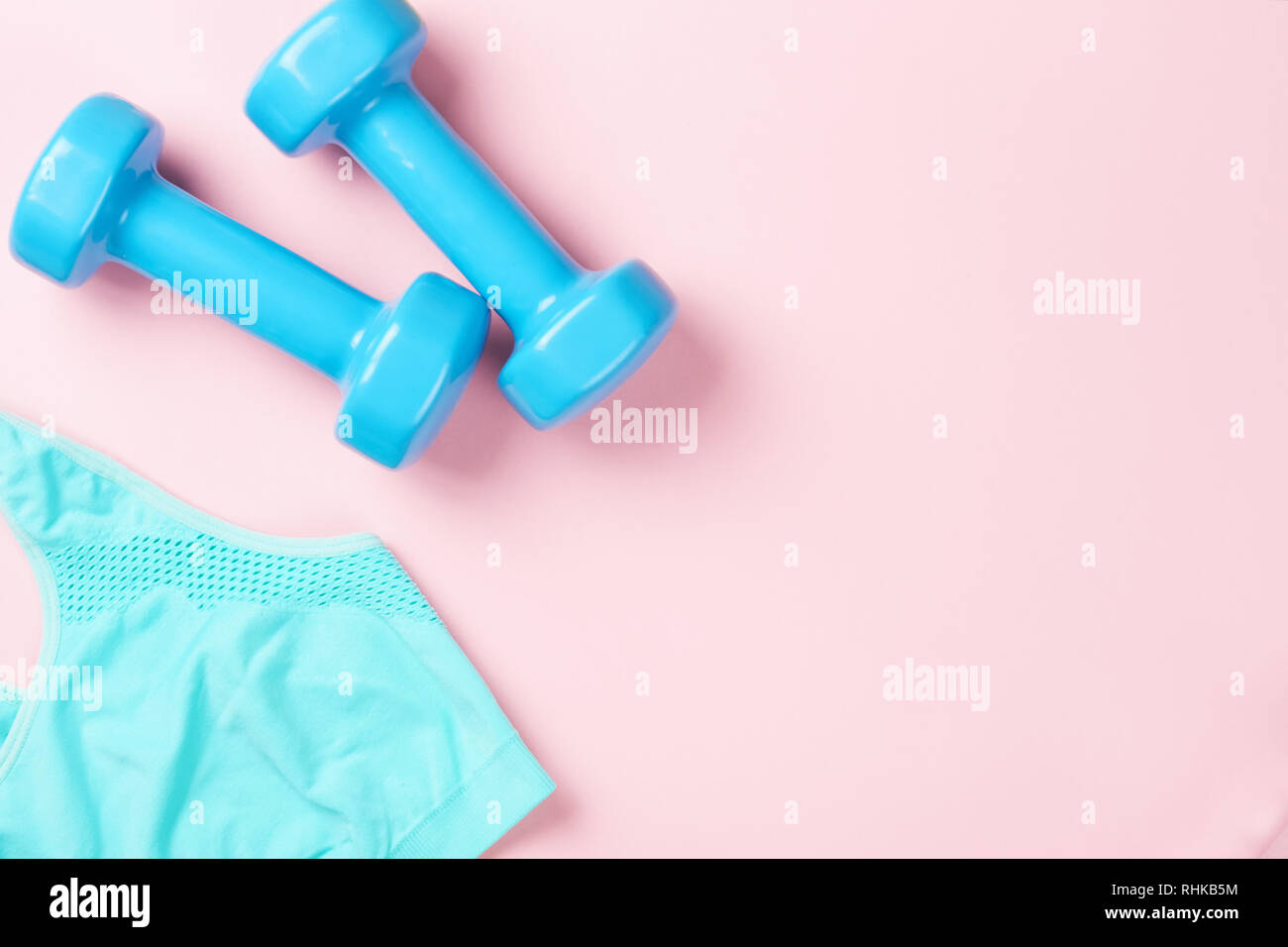 Soutien-gorge sport et haltères bleu sur fond rose, vue du dessus avec l'exemplaire de l'espace. Concept de remise en forme Banque D'Images