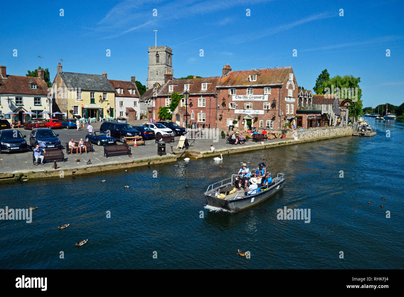 Les gens sur une petite embarcation à moteur se déplaçant le long de la rivière Frome. Bâtiments du quai, Wareham, dans le Dorset, Royaume-Uni : le vieux grenier, café et bar. Banque D'Images Les gens sur une petite embarcation à moteur se déplaçant le long de la rivière Frome. Bâtiments du quai, Wareham, dans le Dorset, Royaume-Uni : le vieux grenier, café et bar. Banque D'Images