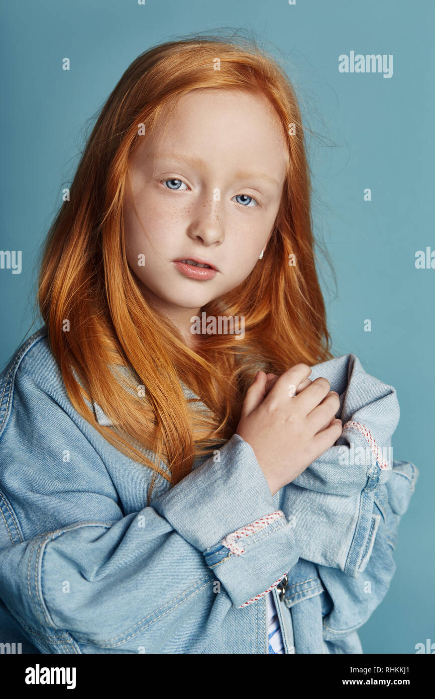 Bebe Fille Belle Rousse Aux Cheveux Longs Dans Un Grand Bleu Veste En Jean Longue Vetements Mode Portrait De Jeune Fille Printemps Rouge Sur Fond Bleu Etre Grand Photo Stock Alamy