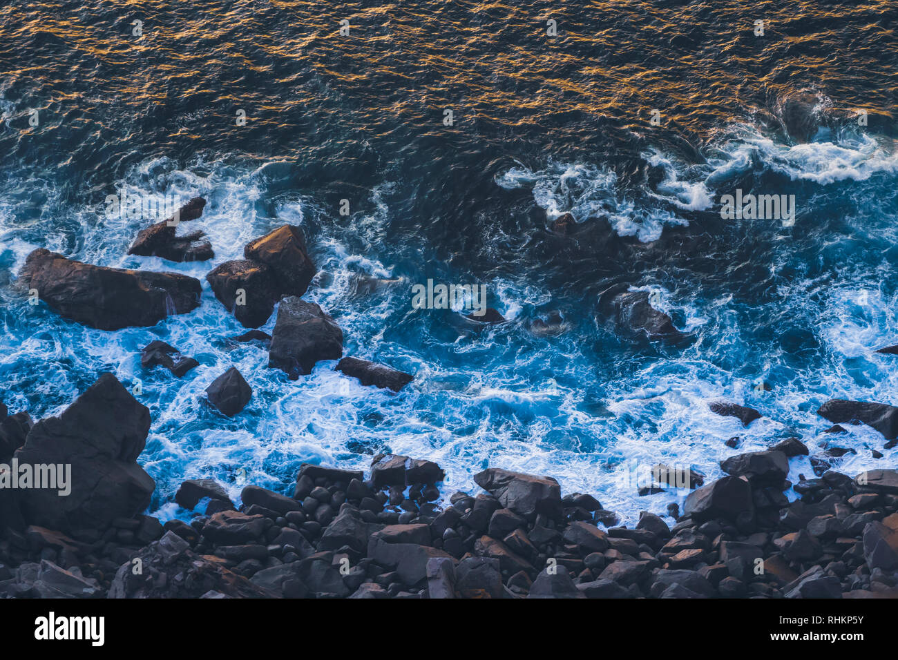 Les vagues d'un bleu profond de l'océan Atlantique sur la côte de basalte foncé frapper avec Golden Sunlight reflecting off vagues au coucher du soleil. Cape Roca Banque D'Images