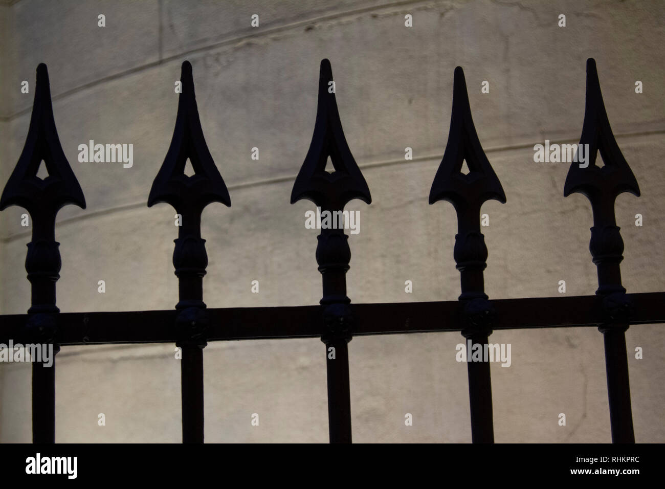Silhouette de poteaux de clôture contre un mur rétroéclairé Banque D'Images