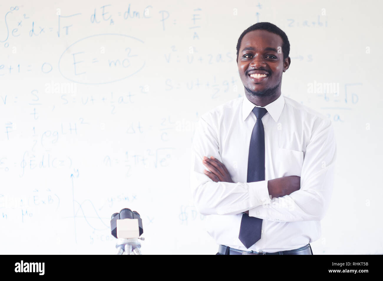 Professeur de sciences de l'Afrique de l'enseignement et souriant dans la tige classe avec microscope. Banque D'Images