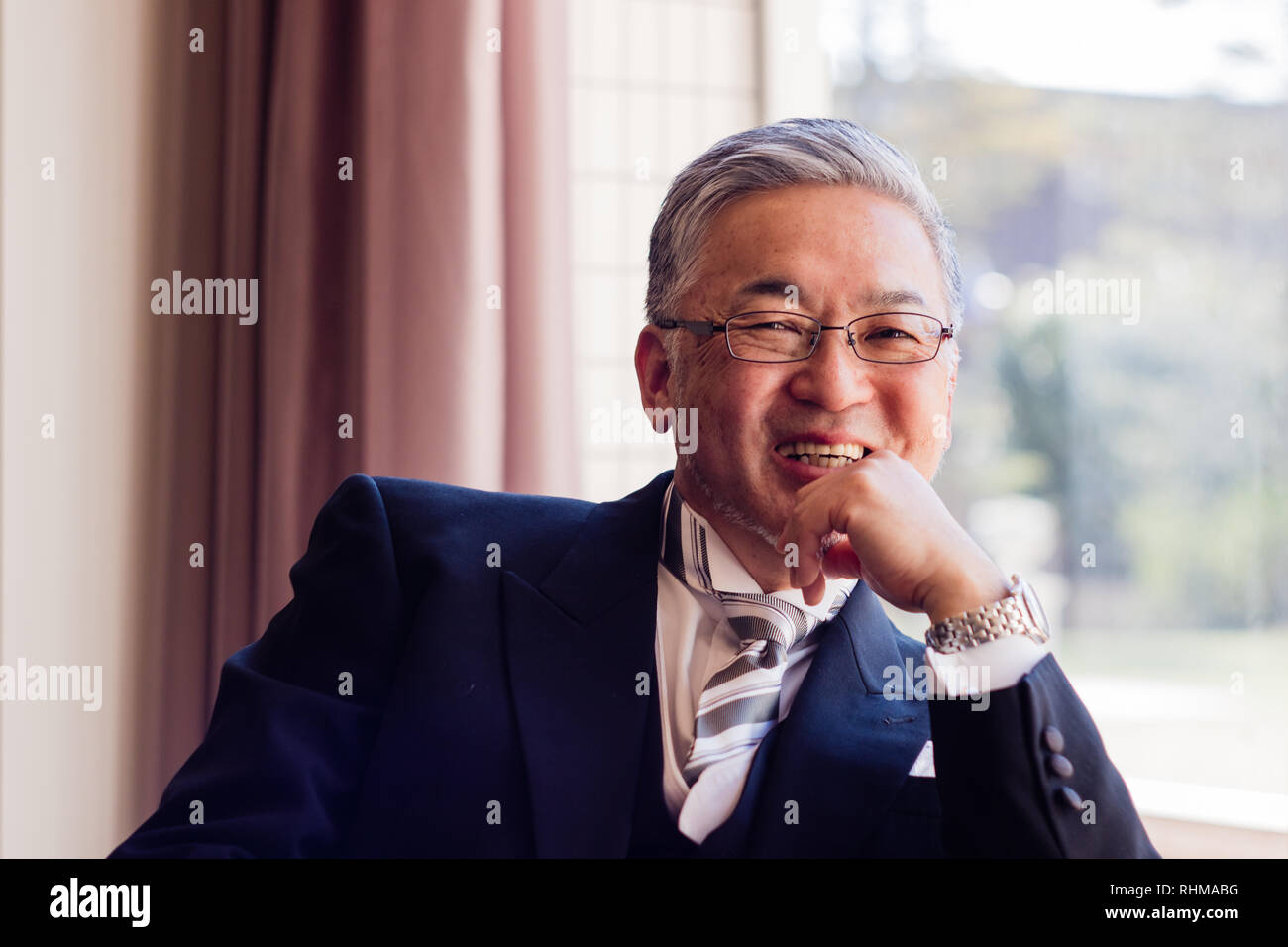 Un beau senior Asian man smiling dans l'appareil photo en vêtements officiels Banque D'Images