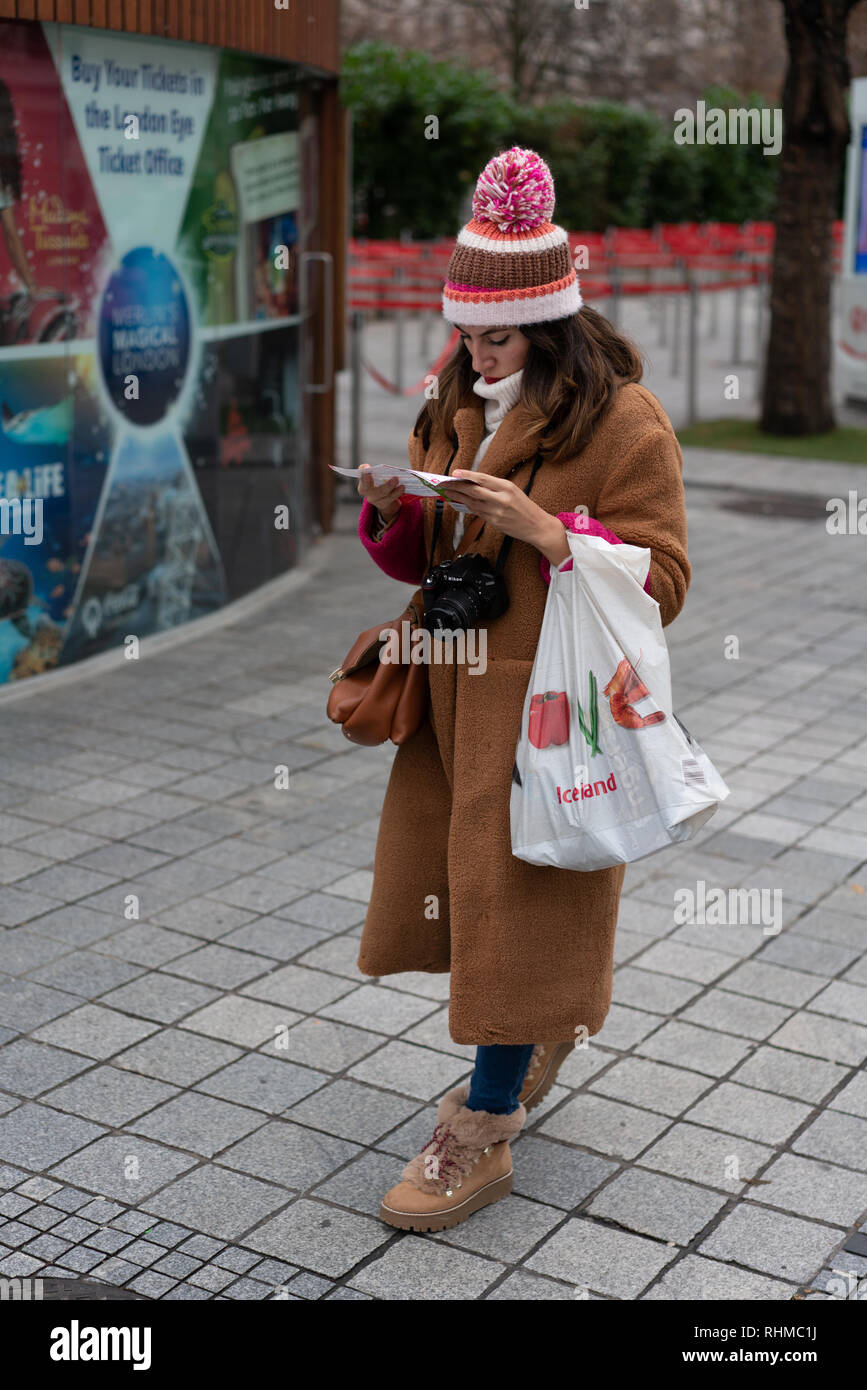 Femme en vêtements d'hiver se lit la carte d'une longue marche une rue dans le centre de Londres Banque D'Images