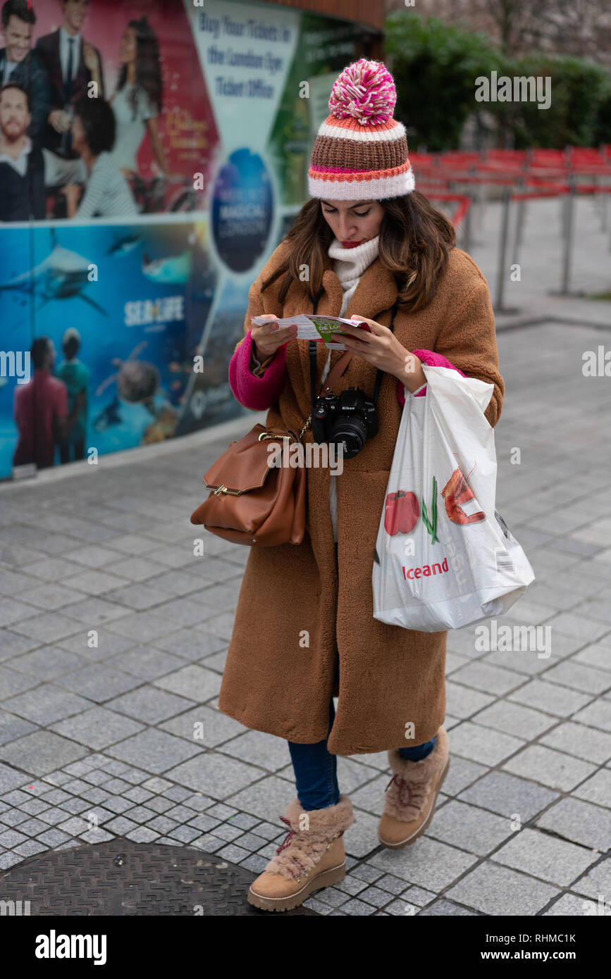 Femme en vêtements d'hiver se lit la carte d'une longue marche une rue dans le centre de Londres Banque D'Images