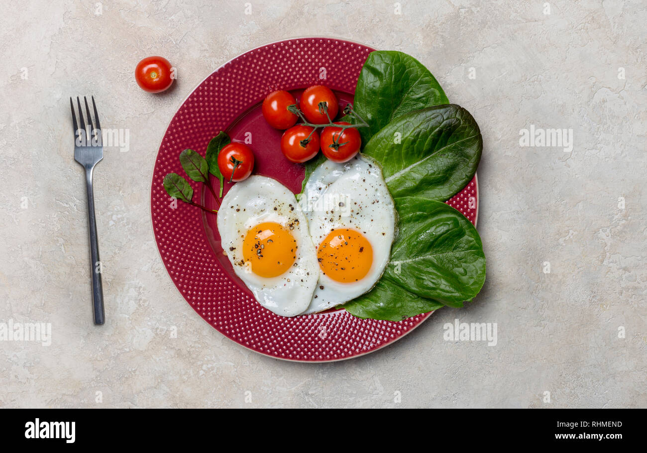 Forme du cœur deux oeufs au plat avec salade de tomates cerises et romano à la fourchette avec plaque rouge sur fond blanc. Concept horizontal de l'italien sain fo Banque D'Images Forme du cœur deux oeufs au plat avec salade de tomates cerises et romano à la fourchette avec plaque rouge sur fond blanc. Concept horizontal de l'italien sain fo Banque D'Images