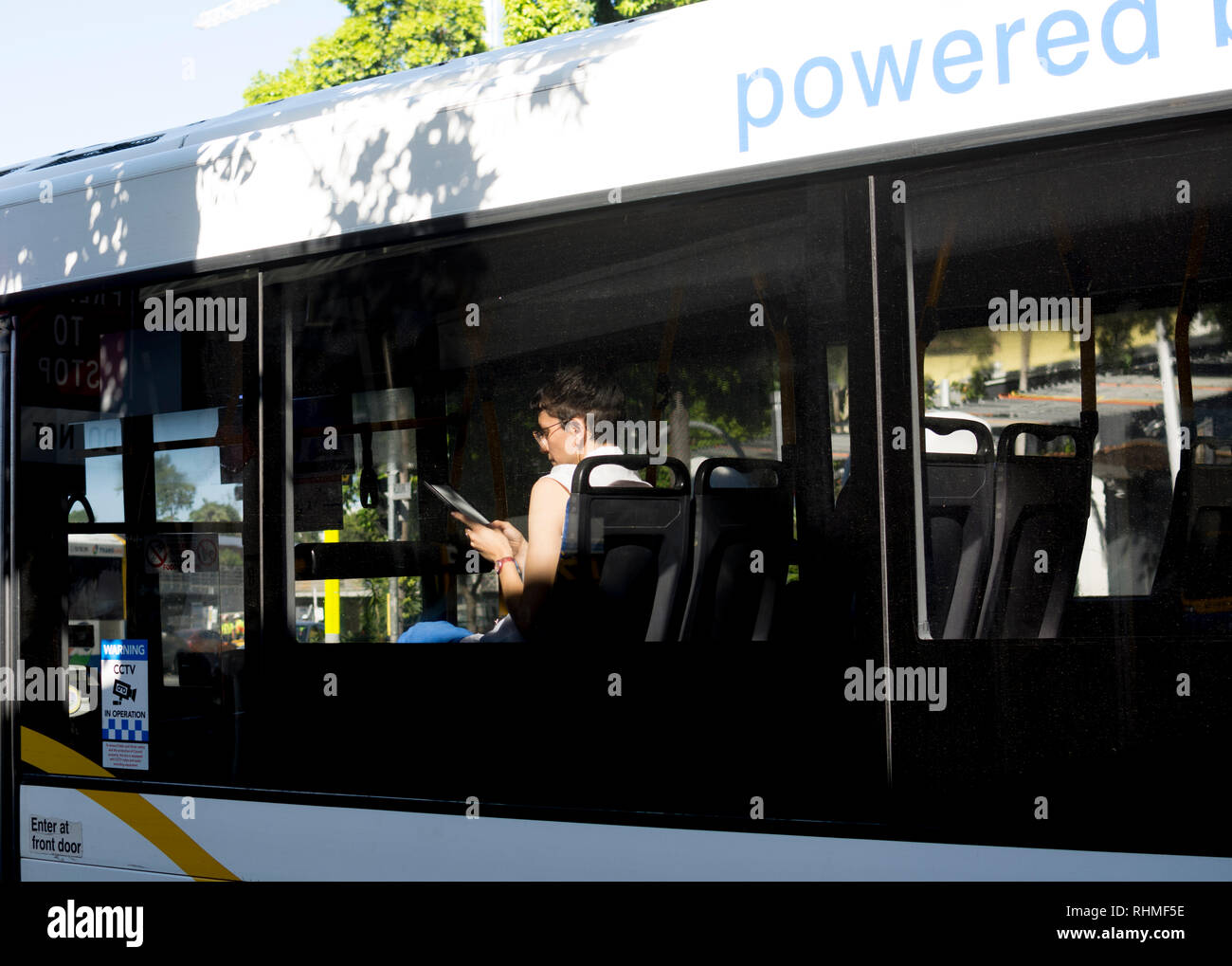 Femme sur un bus de lecture à partir d'une tablette Kindle, Brisbane, Queensland, Australie Banque D'Images