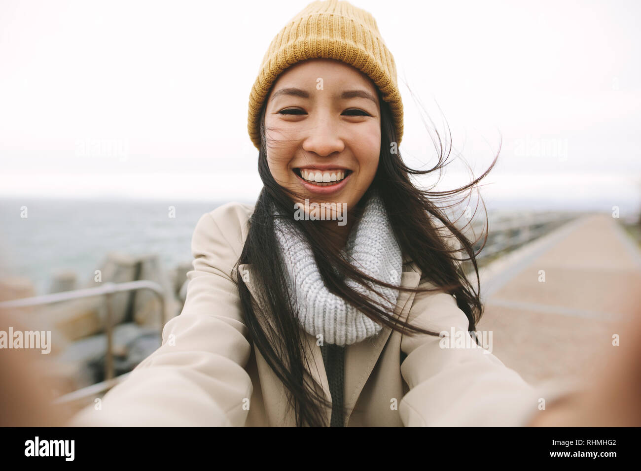 Cheerful Asian women standing outdoors sur un matin d'hiver à bras ouverts. Smiling woman in winter clothes comité permanent à l'extérieur sur une journée froide. Banque D'Images