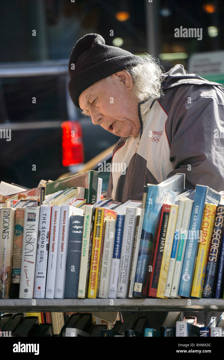 Un homme plus âgé des magasins pour la vente de livres sur les casiers à l'extérieur de la Strand Book Store sur Broadway, à Greenwich Village, New York City. Banque D'Images