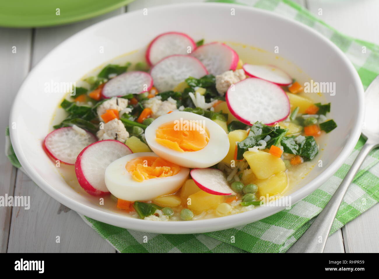 Soupe de printemps aux épinards, pomme de terre, carotte, chou-fleur, radis, petits pois et oeuf dur Banque D'Images