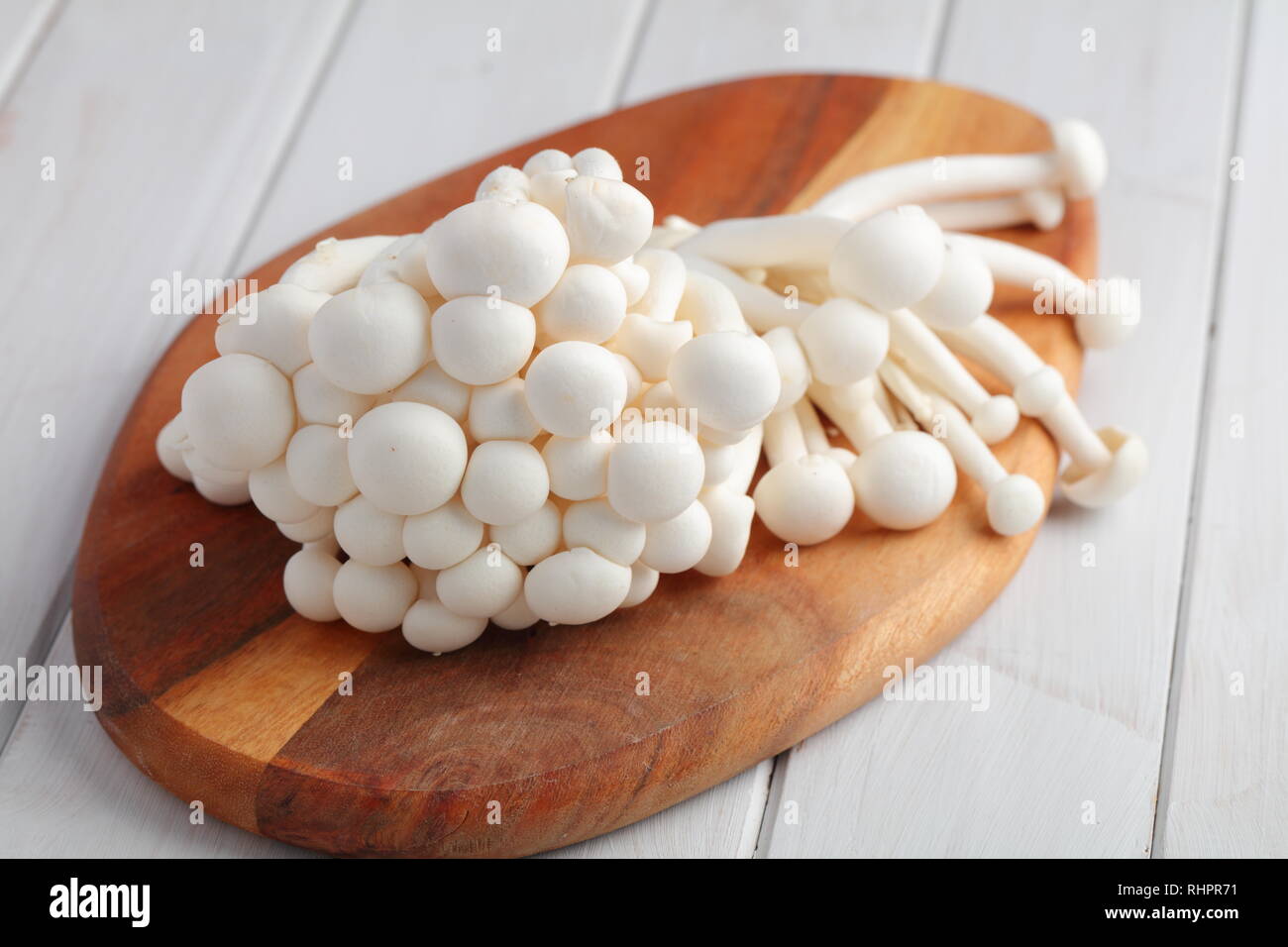 Bouquet de champignons shimeji brut également connu sous le nom de champignons en hêtre blanc sur une planche à découper en bois Banque D'Images