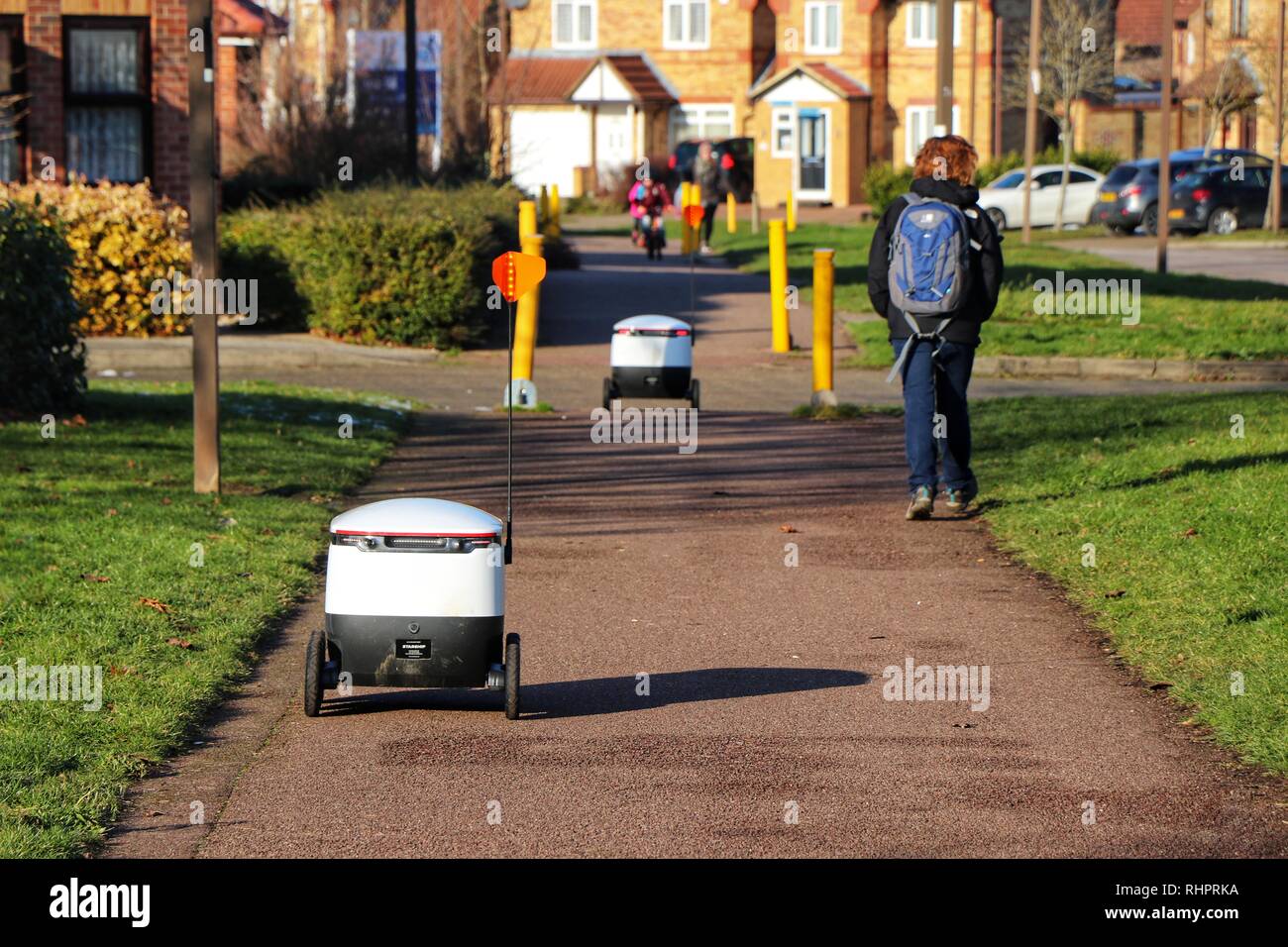 Les piétons passer au sujet de leur vie quotidienne en tant que technologies Starship robots autonomes faire les livraisons d'épicerie de routine autour de Milton Keynes. Banque D'Images