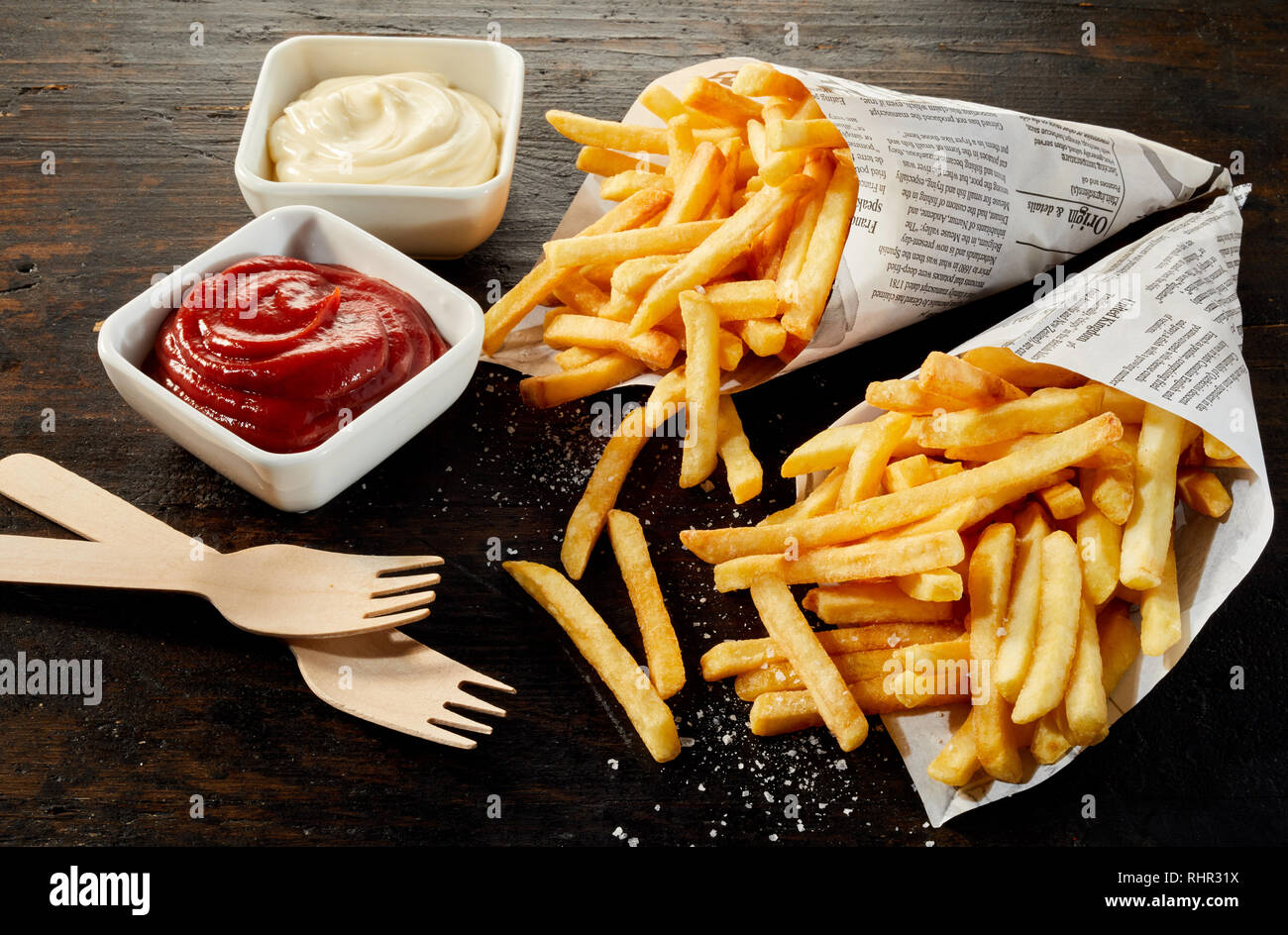 Portions à emporter de croustilles de pommes de terre frites, pommes frites ou frites en cornets en papier avec bols de mayonnaise et ketchup Banque D'Images