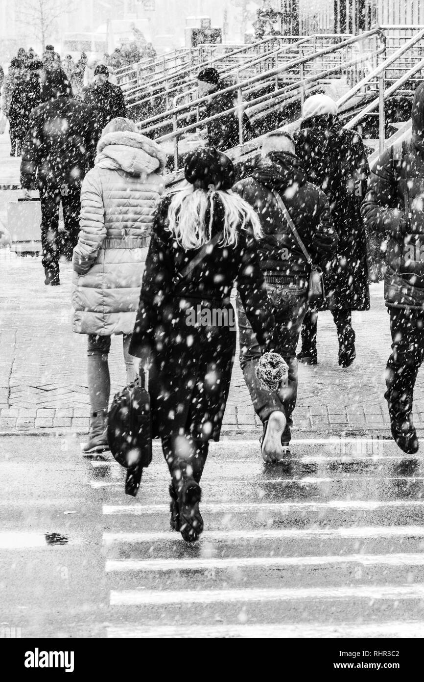 Blizzard dans un environnement urbain. Femme avec sac. Foule de gens se précipiter dans la neige en concordance. Arrière-plan flou abstrait de l'hiver. Banque D'Images