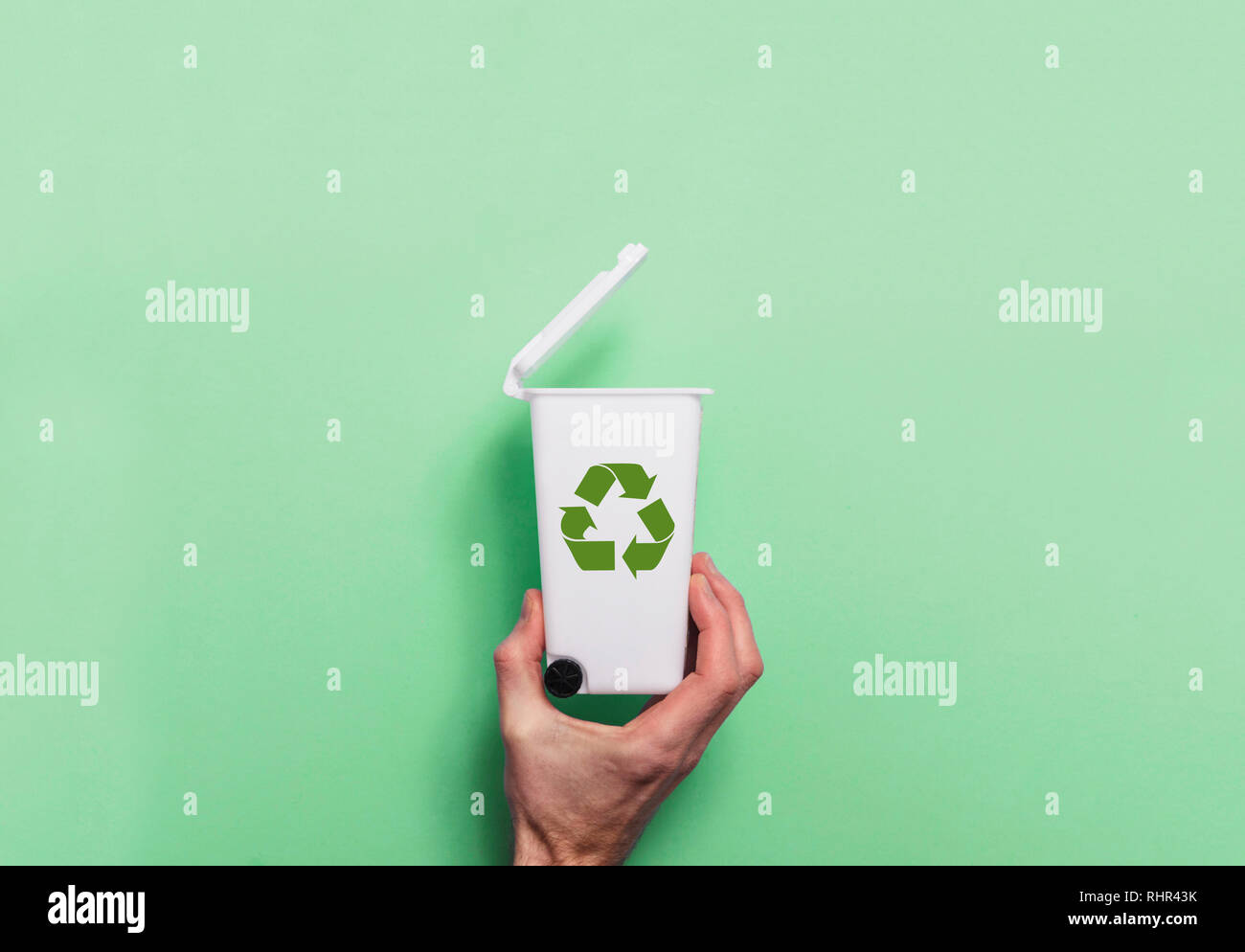 Main tenant le recyclage poubelle sur fond vert Banque D'Images