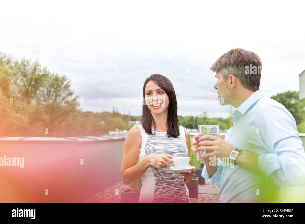 Smiling businesswoman with colleague au cours de pause café en terrasse bureau Banque D'Images Smiling businesswoman with colleague au cours de pause café en terrasse bureau Banque D'Images