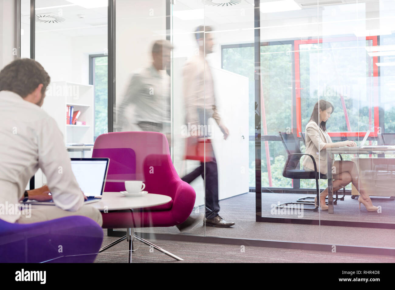 Businessman working on laptop in boardroom avec des collègues de bureau à l'arrière-plan Banque D'Images