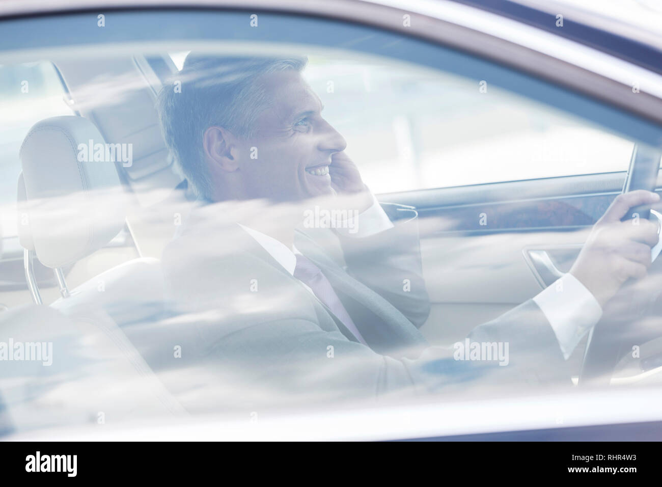 Smiling mature woman talking on mobile phone while driving car Banque D'Images