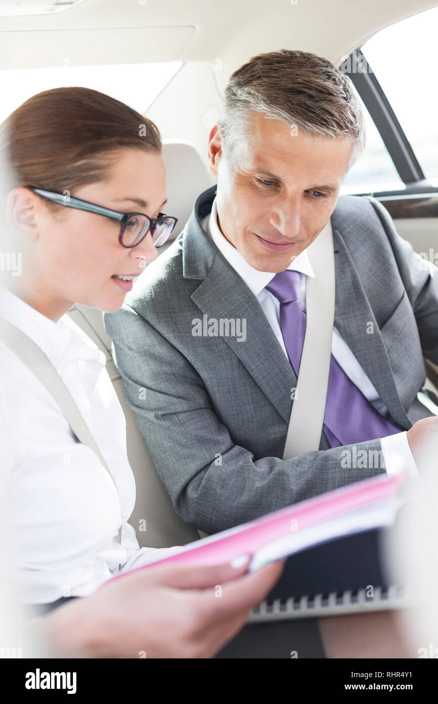 Les professionnels à discuter sur ordinateur portable et documents pendant que sitting in car Banque D'Images
