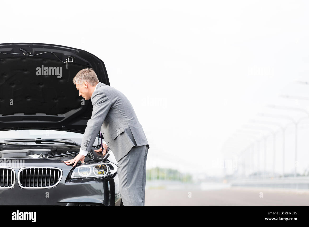 Homme d'affaires à la voiture chez ventilation against sky Banque D'Images