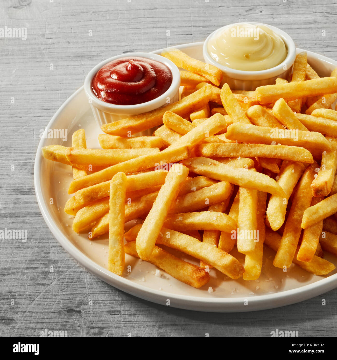 Assiette de frites dorées, chips, Pommes Frites ou avec peu de bols de sauce tomate et de la mayonnaise dans une vue en gros plan, format carré Banque D'Images