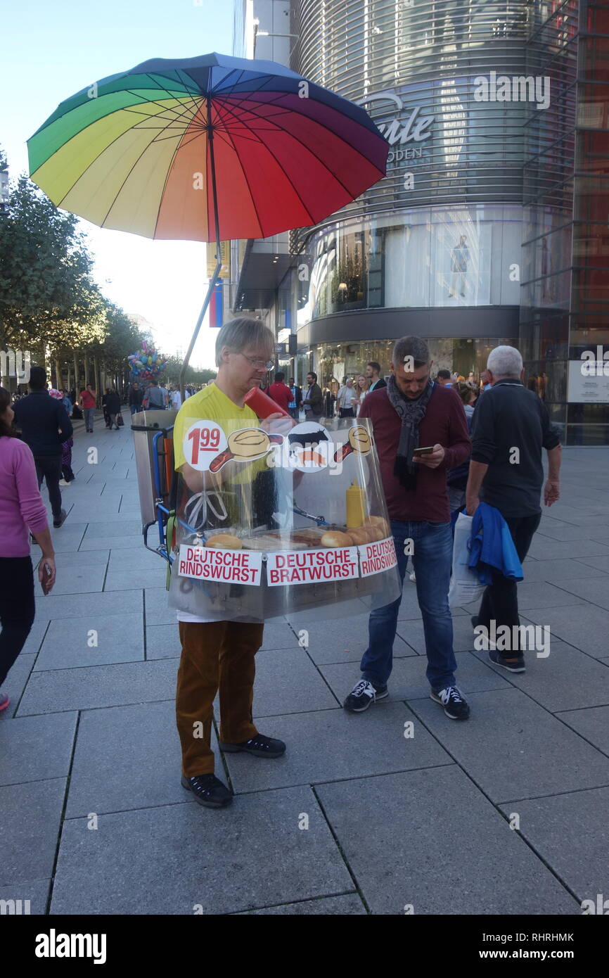 Un vendeur de rue avec un gril portatif vend des saucisses Bratwurst allemandes sur la rue Zeil à Francfort am Main. Banque D'Images