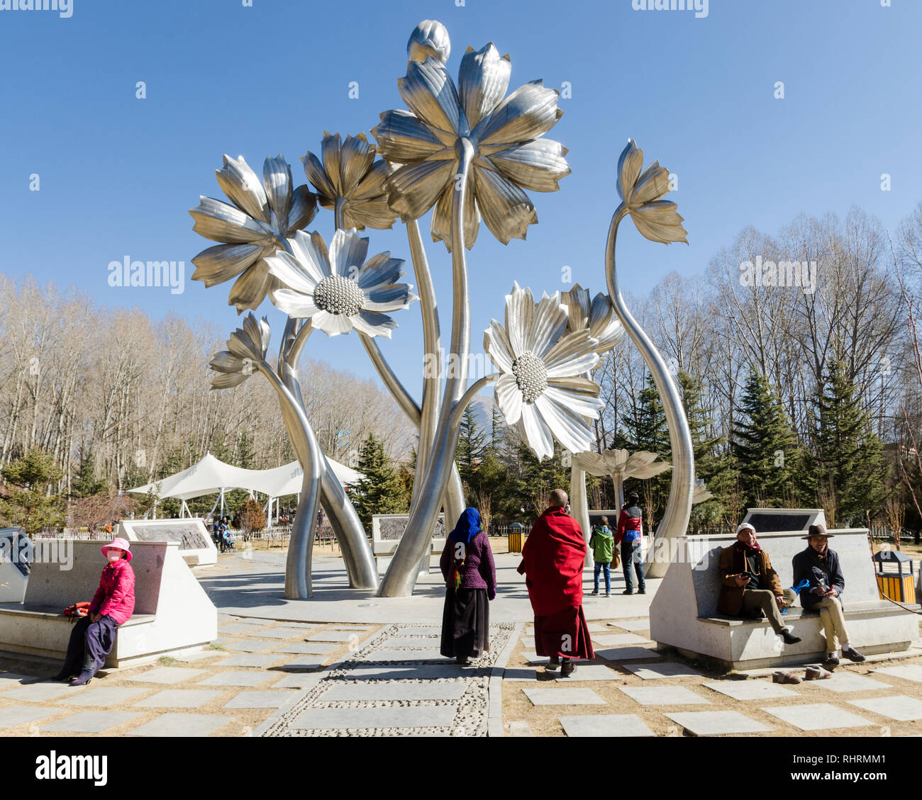 Les Tibétains locaux à côté d'une sculpture de fleurs de grande taille en Zongjiao Lukang park, Lhassa, Tibet Banque D'Images