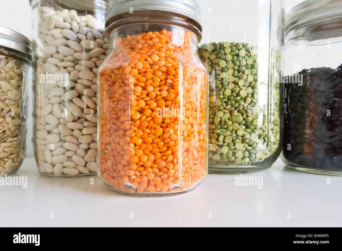 Pots d'ingrédients colorés habilement placé dans un garde-manger moderne blanc - orange, vert, noir et blanc, haricots, pois, lentilles et plus Banque D'Images