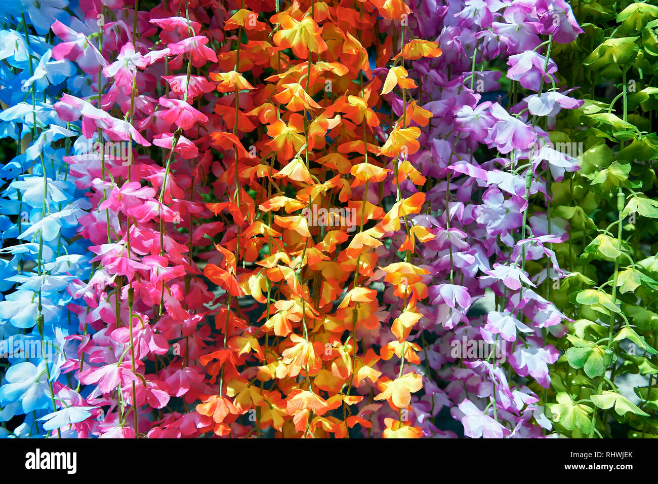 La pendaison des guirlandes de fleurs en plastique coloré en vente en Asie. Banque D'Images