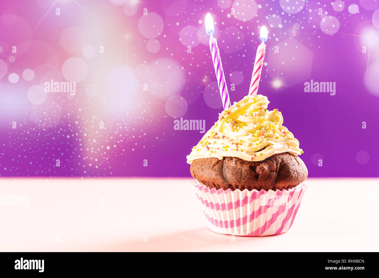Birthday cupcake avec deux bougie sur fond violet et rose. Banque D'Images